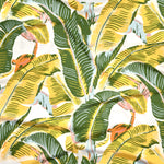 Close up of gently draped printed linen with bold banana leaf in yellow and green with accents of light blue, pink and orange on white. 