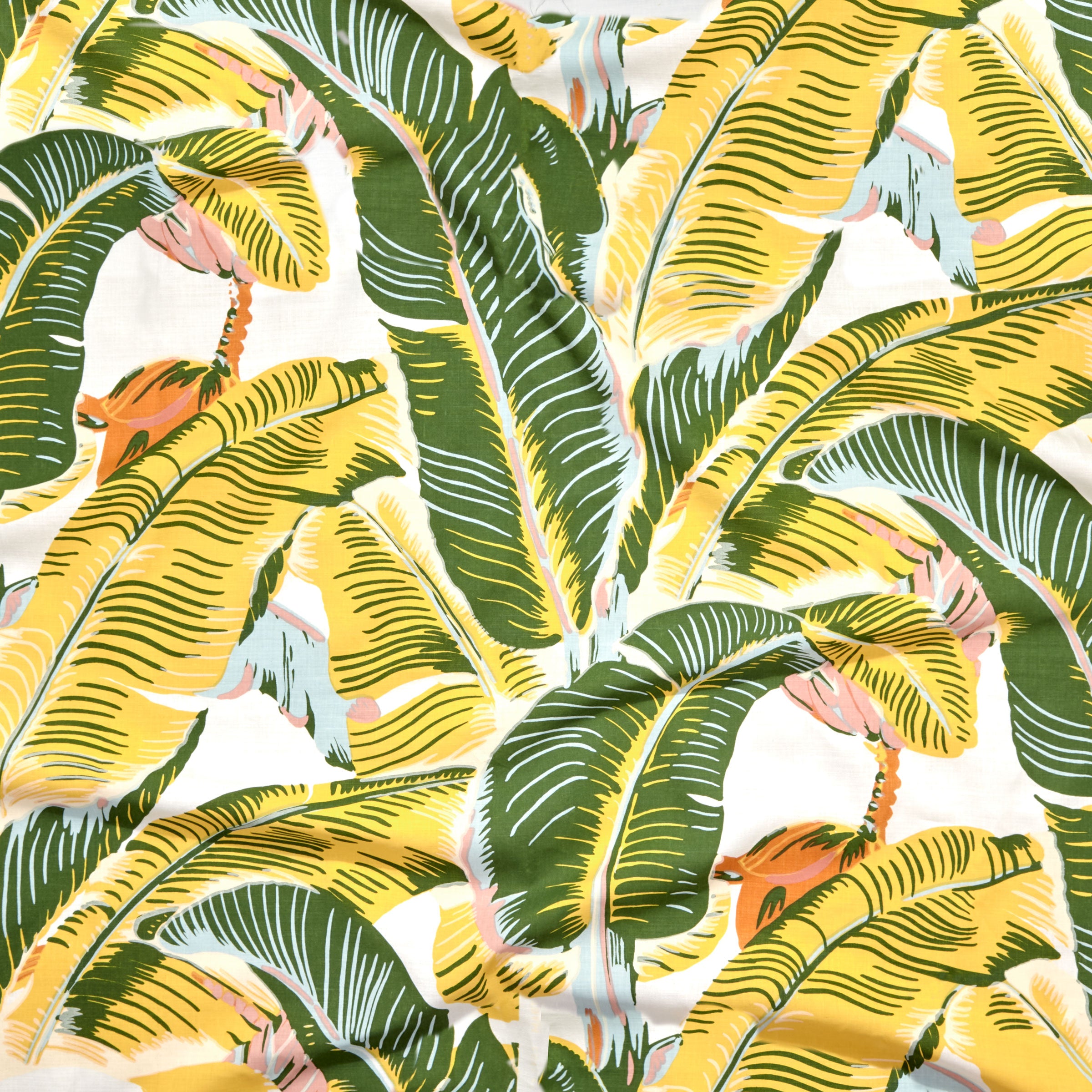 Close up of gently draped printed linen with bold banana leaf in yellow and green with accents of light blue, pink and orange on white. 
