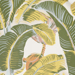 A close-up of a tropical banana leaf pattern with large green and yellow leaves, peach-colored flowers, and a cream background.