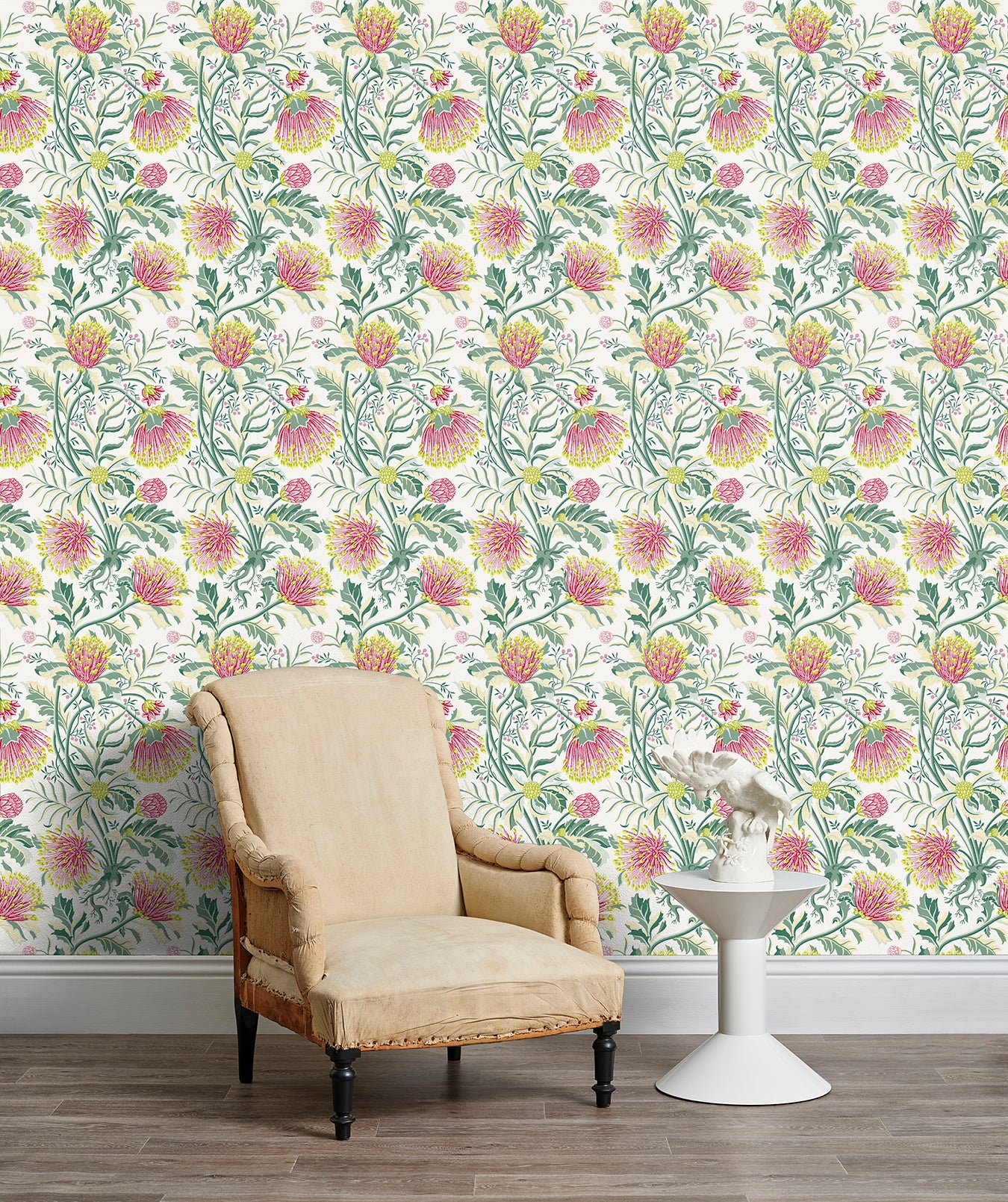 Armchair and end table in front of a wall papered in a dense floral print in pink, yellow, green and white.