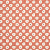 Detail of fabric in a repeating blossom print in white on a burnt orange field.