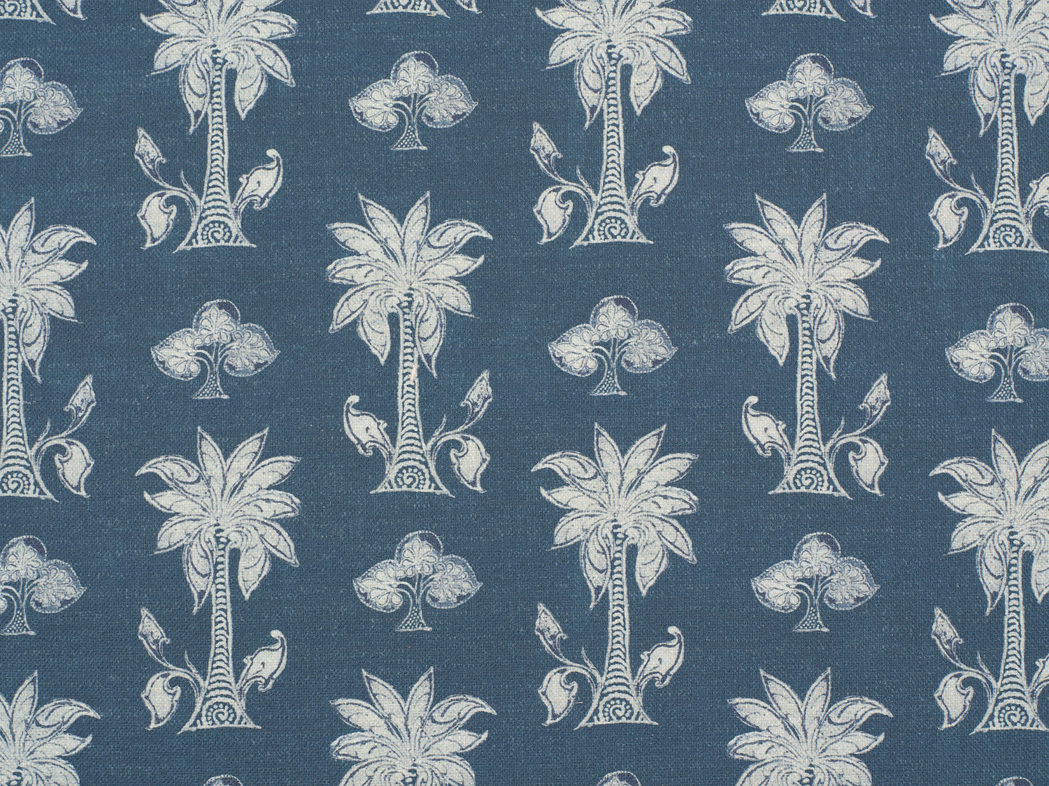 Detail of fabric in a playful palm tree print in white and navy on a blue field.