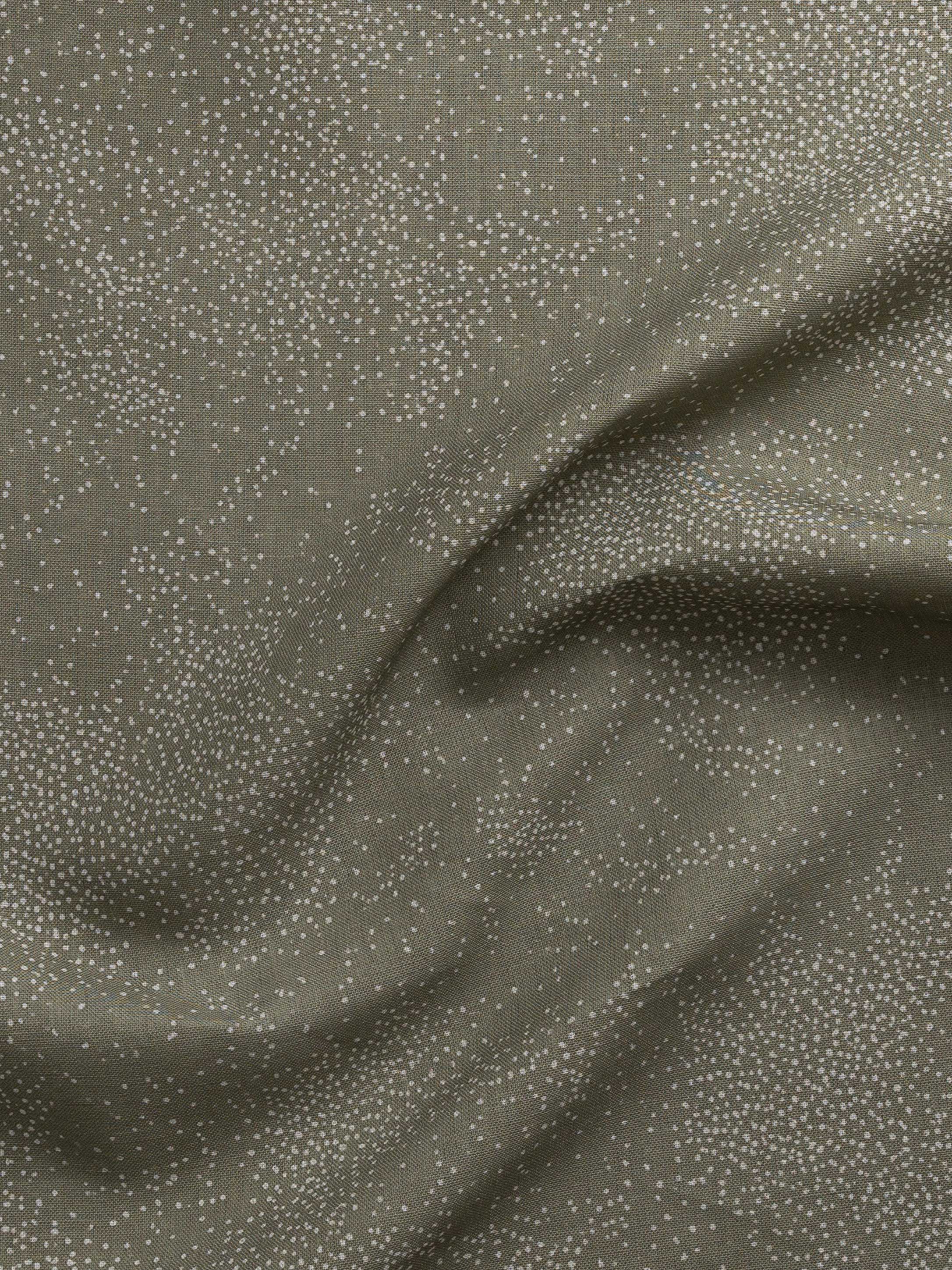 Detail of gently draped printed fabric with a white celestial dotted pattern on a muted sage green background. 