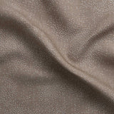 Detail of gently draped printed fabric with a white celestial dotted pattern on a warm beige background. 