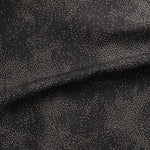 Detail of gently draped printed fabric with a white celestial dotted pattern on a muted black background. 