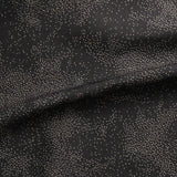 Detail of gently draped printed fabric with a white celestial dotted pattern on a muted black background. 
