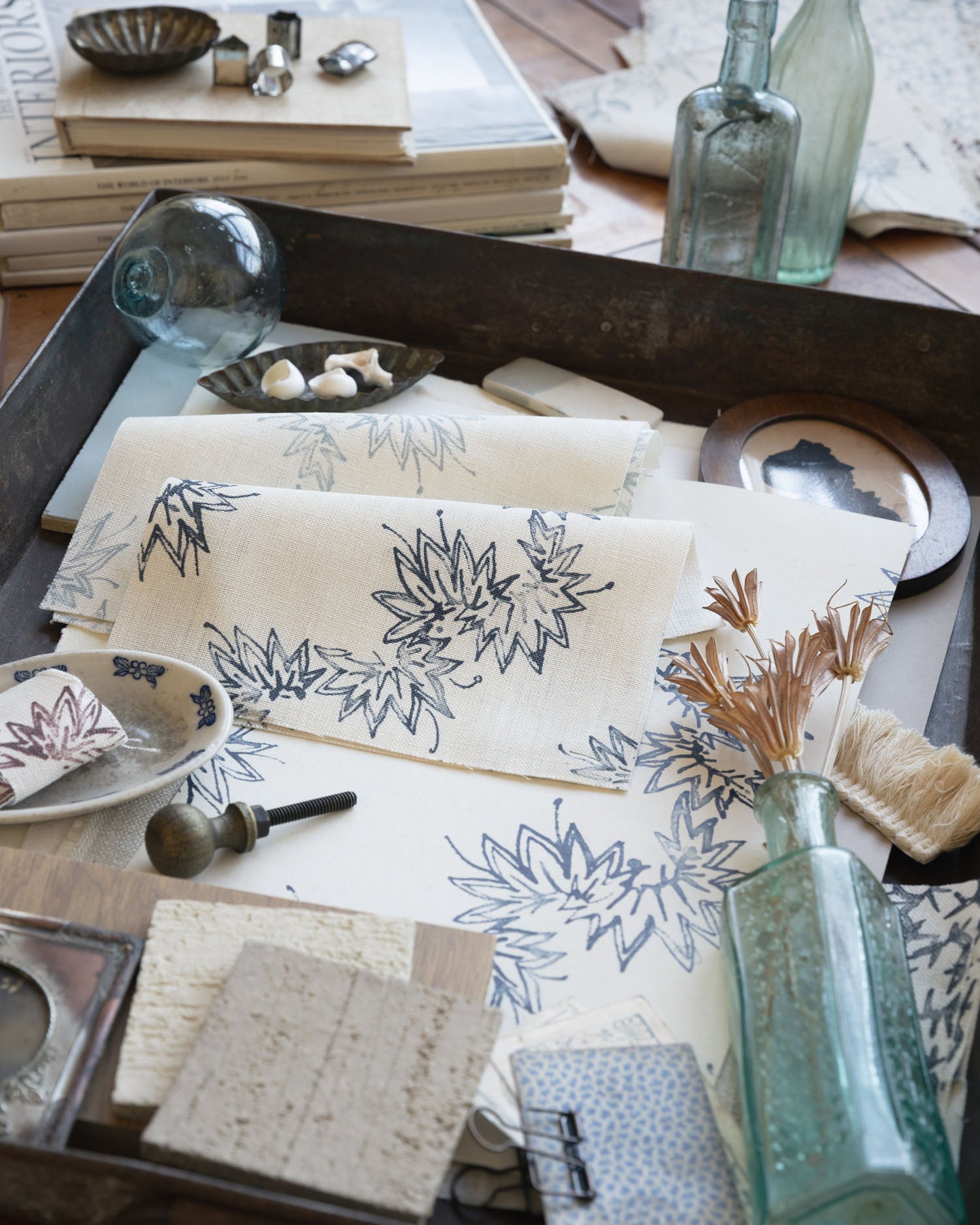Desk setting with floral-patterned paper, inkwell, and bottles on a wooden surface.