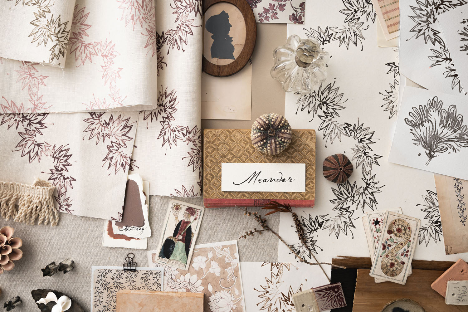 Mood board withecorative items including fabric swatches, photos, and a framed name card on a textured surface.