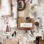 Mood board withecorative items including fabric swatches, photos, and a framed name card on a textured surface.