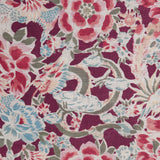 Detail of a linen fabric in a painterly floral pattern in shades of blue, green and pink on a maroon field.