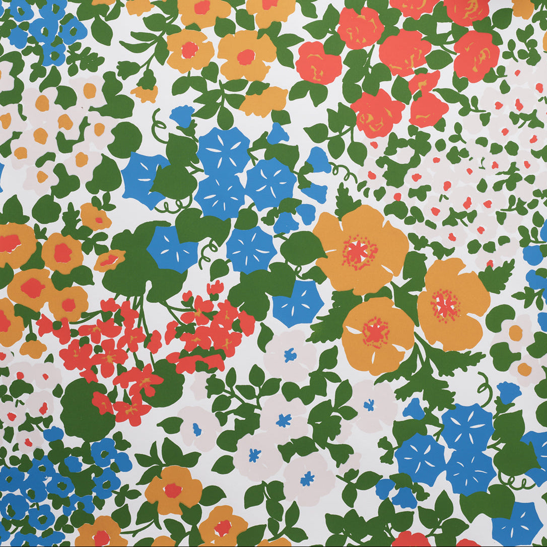 Close up of wallpaper with a dense flower and leaf pattern in shades of yellow, orange, blue, green and white. 