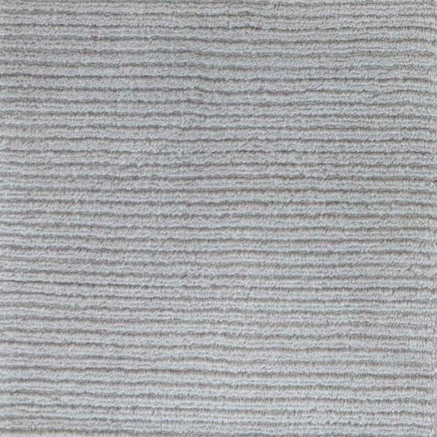 Close up of broadloom carpet with solid cut pile ribbed stripe in grey.