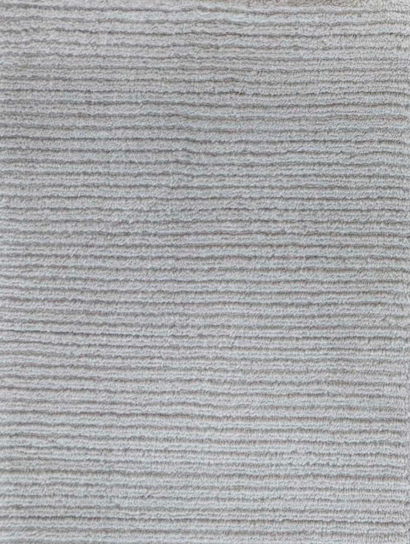 Close up of broadloom carpet with solid cut pile ribbed stripe in grey.