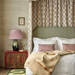 Bedroom with a canopy bed, patterned headboard, and wooden nightstand.