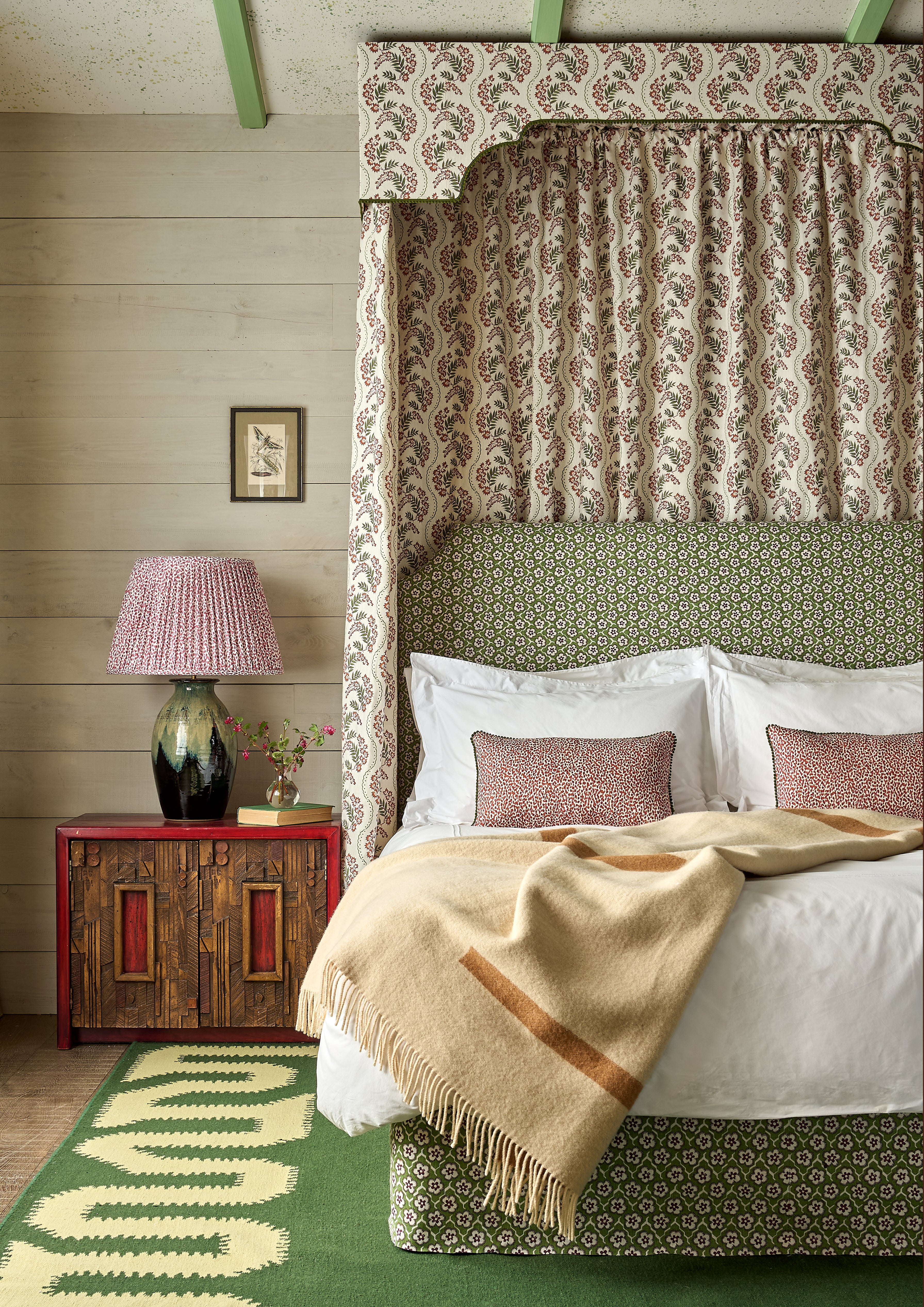 Bedroom with a canopy bed, patterned headboard, and wooden nightstand.