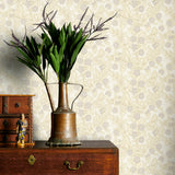 Decorative vase with plants on a wooden dresser against a soft yellow floral patterned wallpaper.
