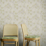 Two wooden chairs with green cushions against a yellow and grey floral patterned wallpaper.