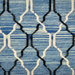 Detail of flatwoven rug with a black and white lattice design over a mottled blue ground