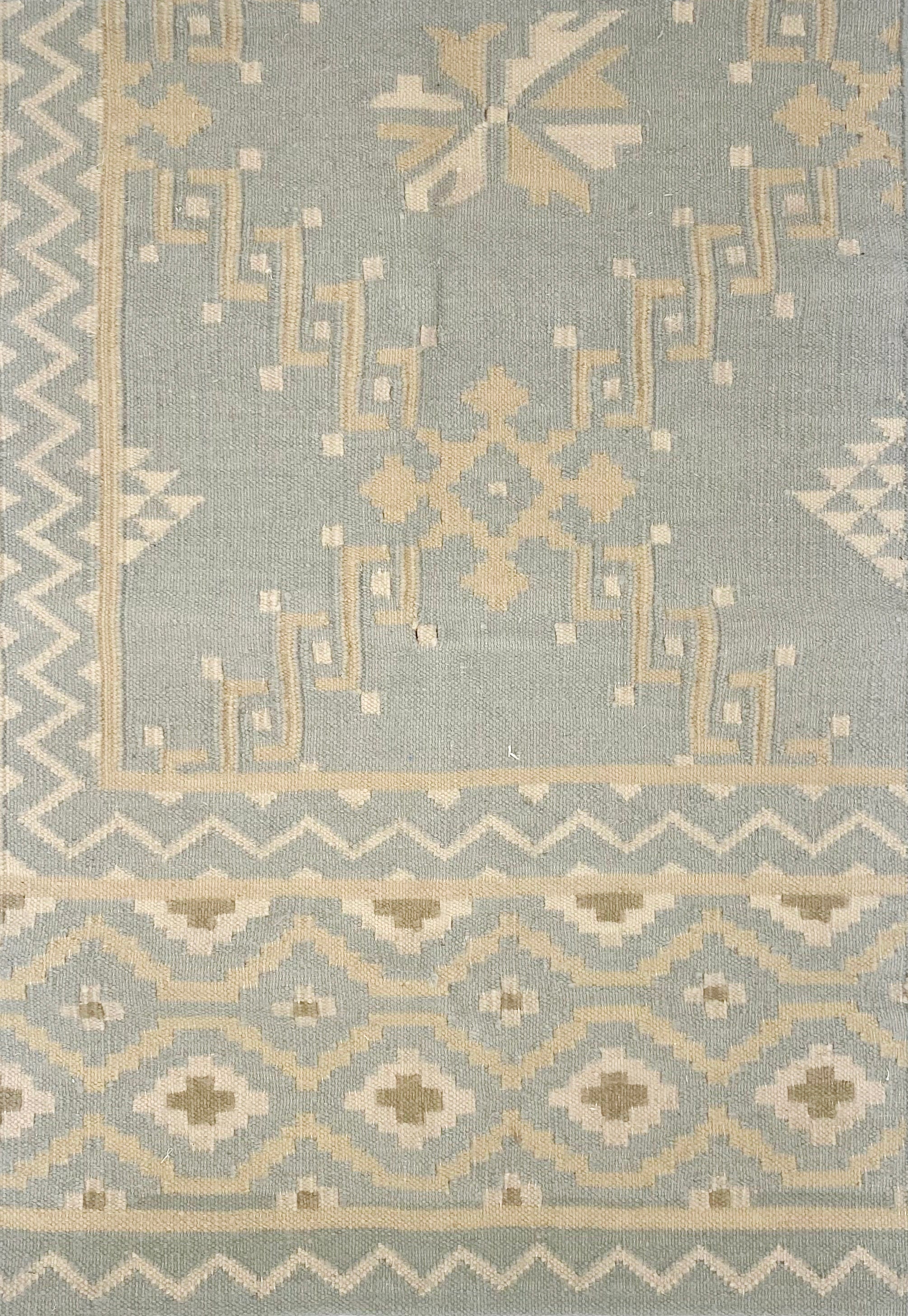 Patterned rug with geometric design on a light blue background