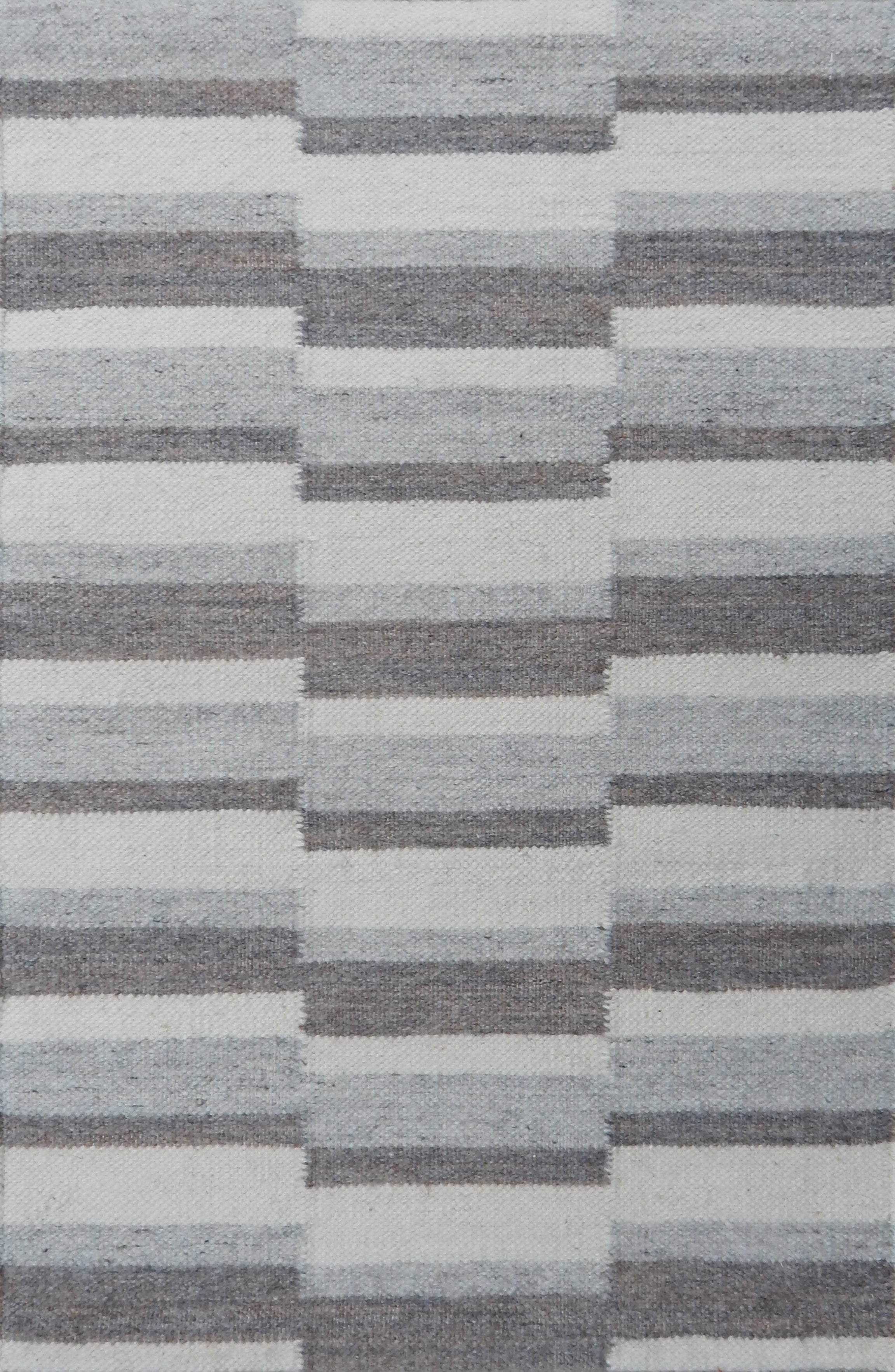 Flatweave rug in a broken stripe in shades of grey and cream.