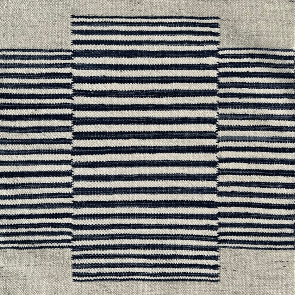 Flatweave rug in with a color central broken stripe in black and white on a beige field. 