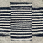 Flatweave rug in with a color central broken stripe in black and white on a beige field. 