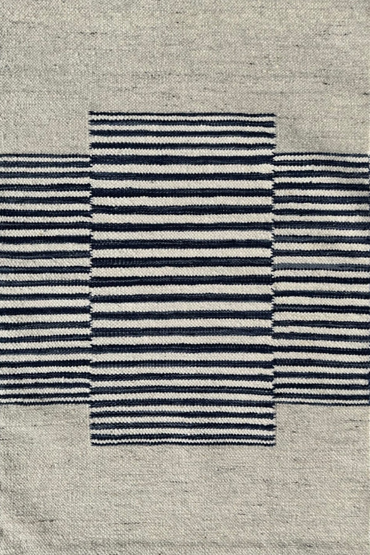Flatweave rug in with a color central broken stripe in black and white on a beige field. 