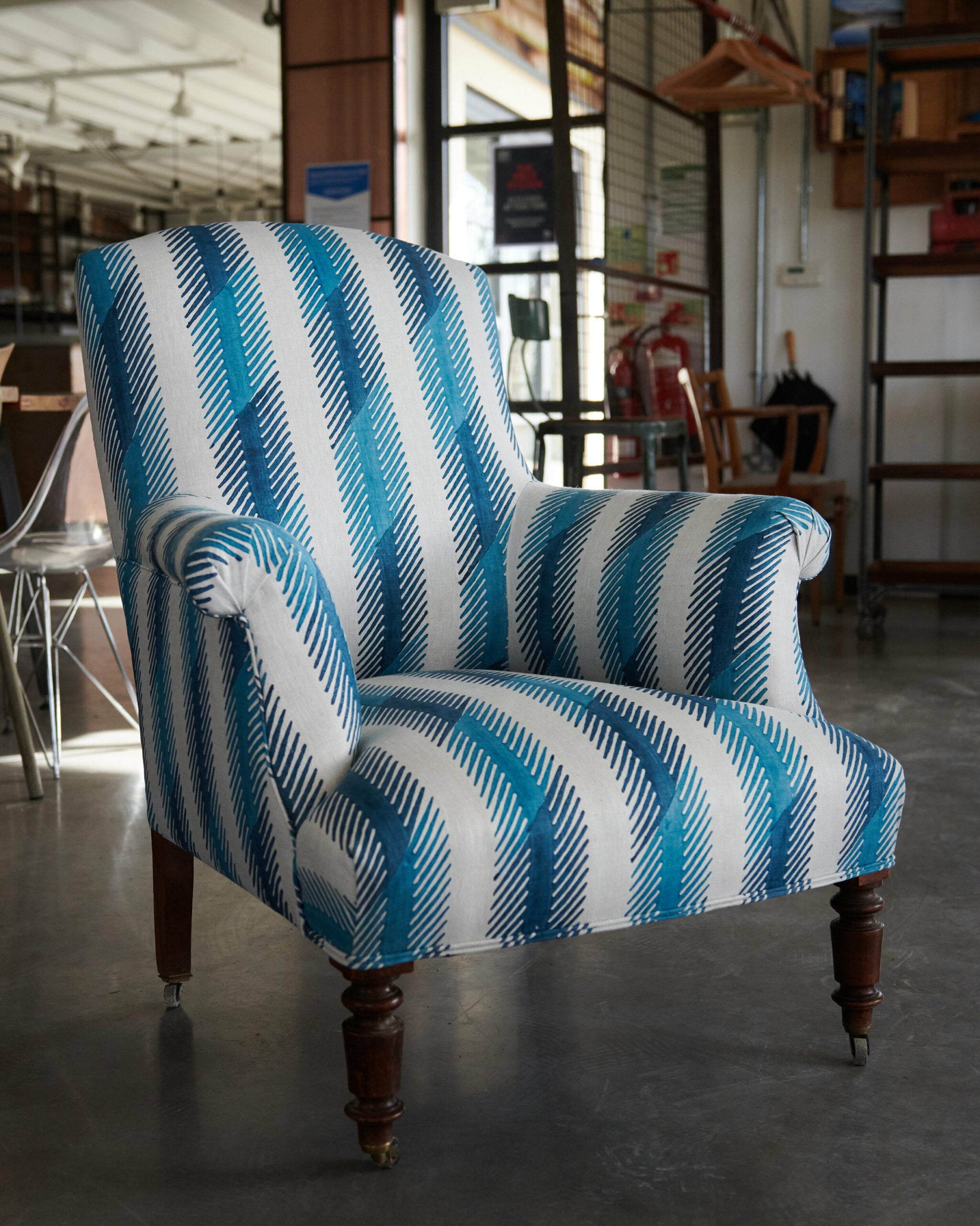 Armchair upholstered in a a playful broken stripe pattern in mottled navy on a cream field.