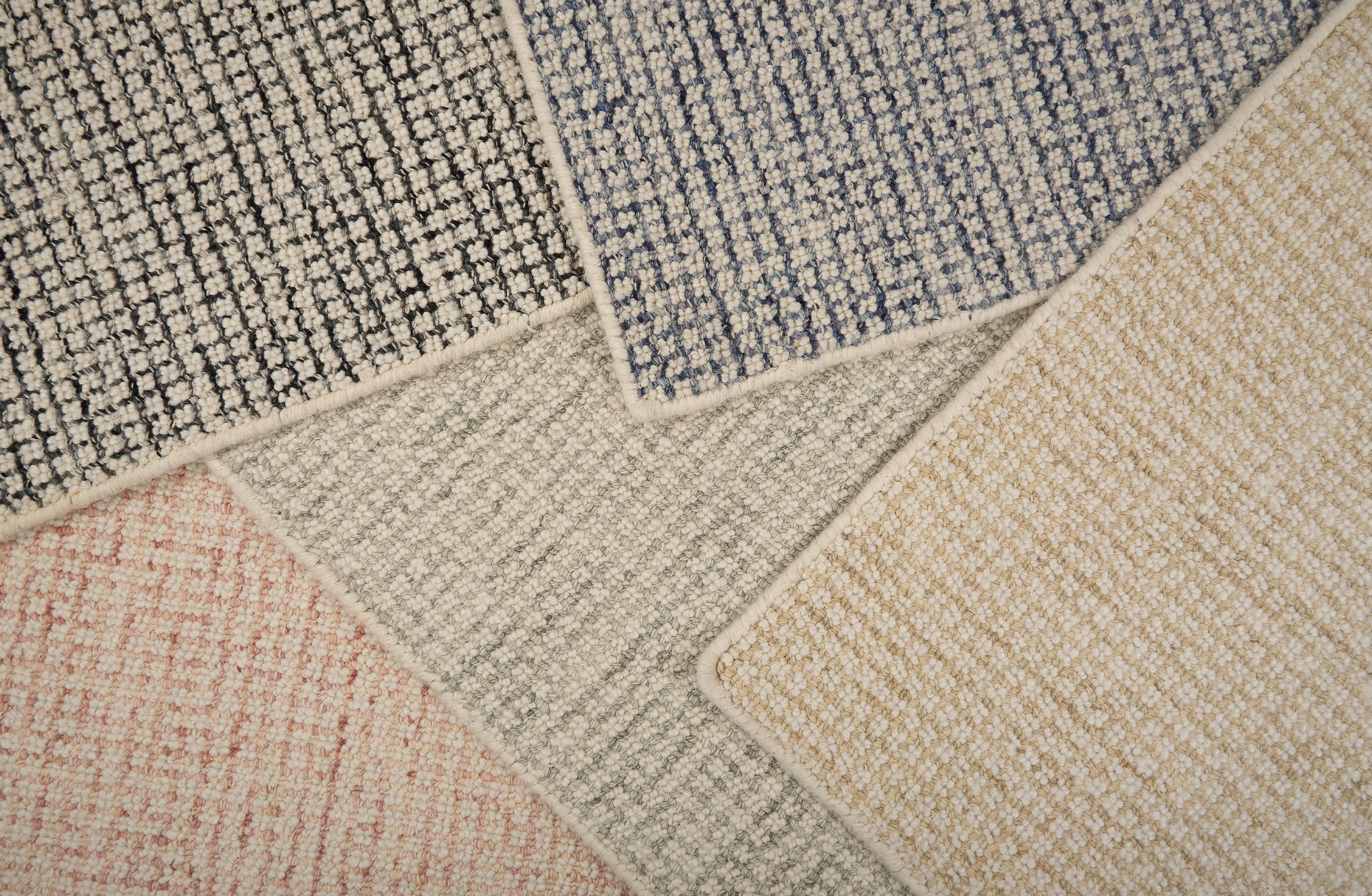 Stack of broadloom carpet samples in a checkered pattern in a range of colors. 