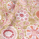 Draped printed linen in a handdrawn playful floral design in coral, lilac and red against a tan field. 