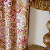 Curtain in printed linen in a handdrawn playful floral design in coral, lilac and red against a tan field. 