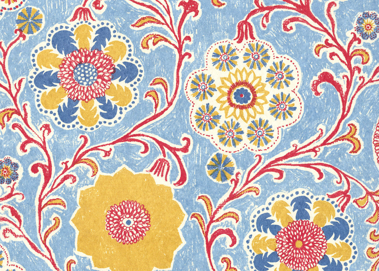 Wallpaper in a handdrawn playful floral design in red, yellow, green and blue on a light blue field.