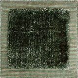 Handloomed rug with green-tan border and raised cut pile shag field in forest green.