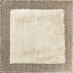 Handloomed rug with neutral border and raised cut pile shag field in beige. 