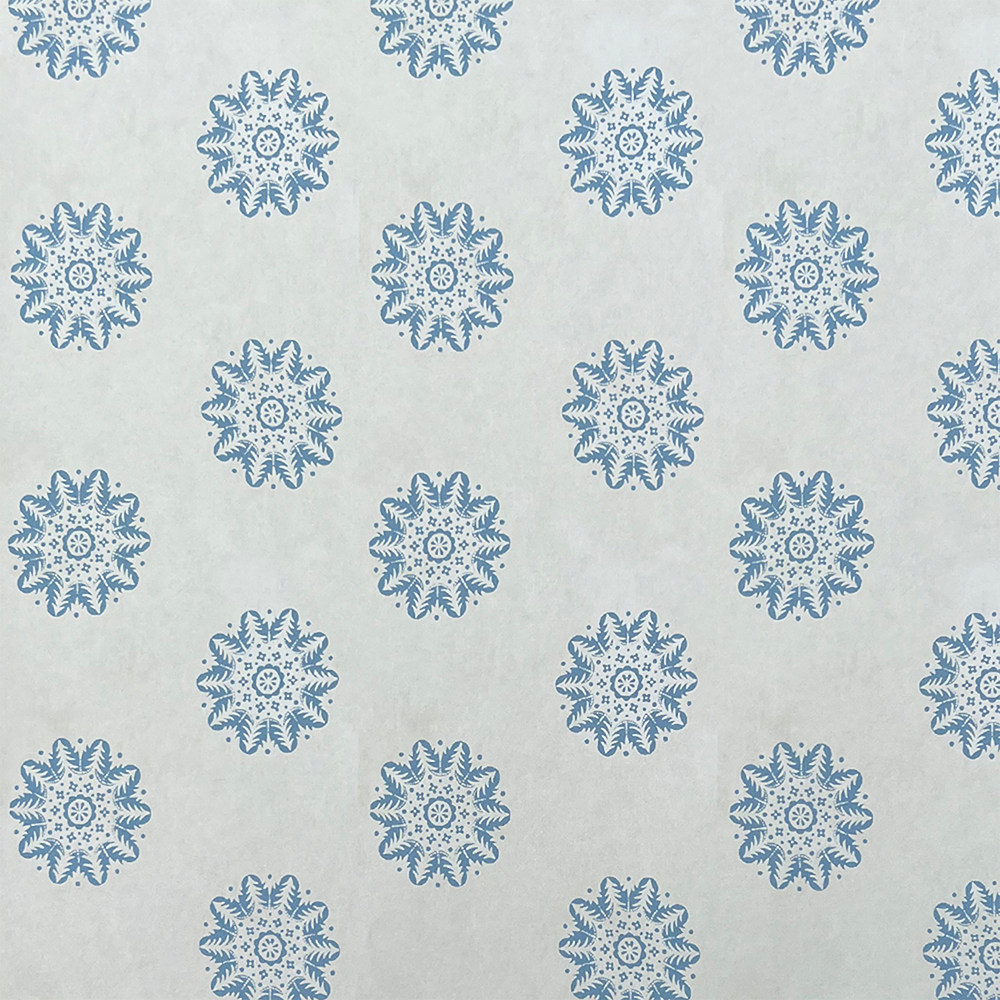 Detail of wallpaper in a playful repeating floral print in blue on a cream field.