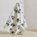 A large piece of draped fabric in an abstract geometric print in mottled green and cream on a white field.