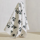 A large piece of draped fabric in an abstract geometric print in mottled green and cream on a white field.