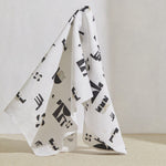 A large piece of draped fabric in an abstract geometric print in charcoal and cream on a white field.