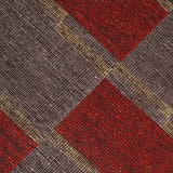 Detail of a handwoven carpet in a geometric design in brown, red with yellow accent. 