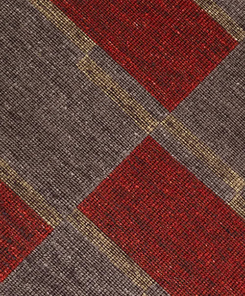Detail of a handwoven carpet in a geometric design in brown, red with yellow accent. 
