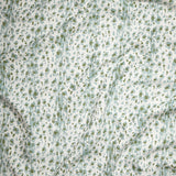 Close up of gently draped Indoor-Outdoor fabric with a painterly animal print in light blue and green on white. 