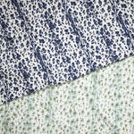 Layered fabric cuttings with a painterly animal print in navy blue and light blue and green on white. 