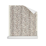 Roll of wallpaper with small scale painterly animal print in taupe and black on white.