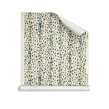 Roll of wallpaper with small scale painterly animal print in tan and dark green on white. 