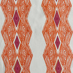 Detail of fabric in an intricate diamond stripe print in orange and pink on a cream field.
