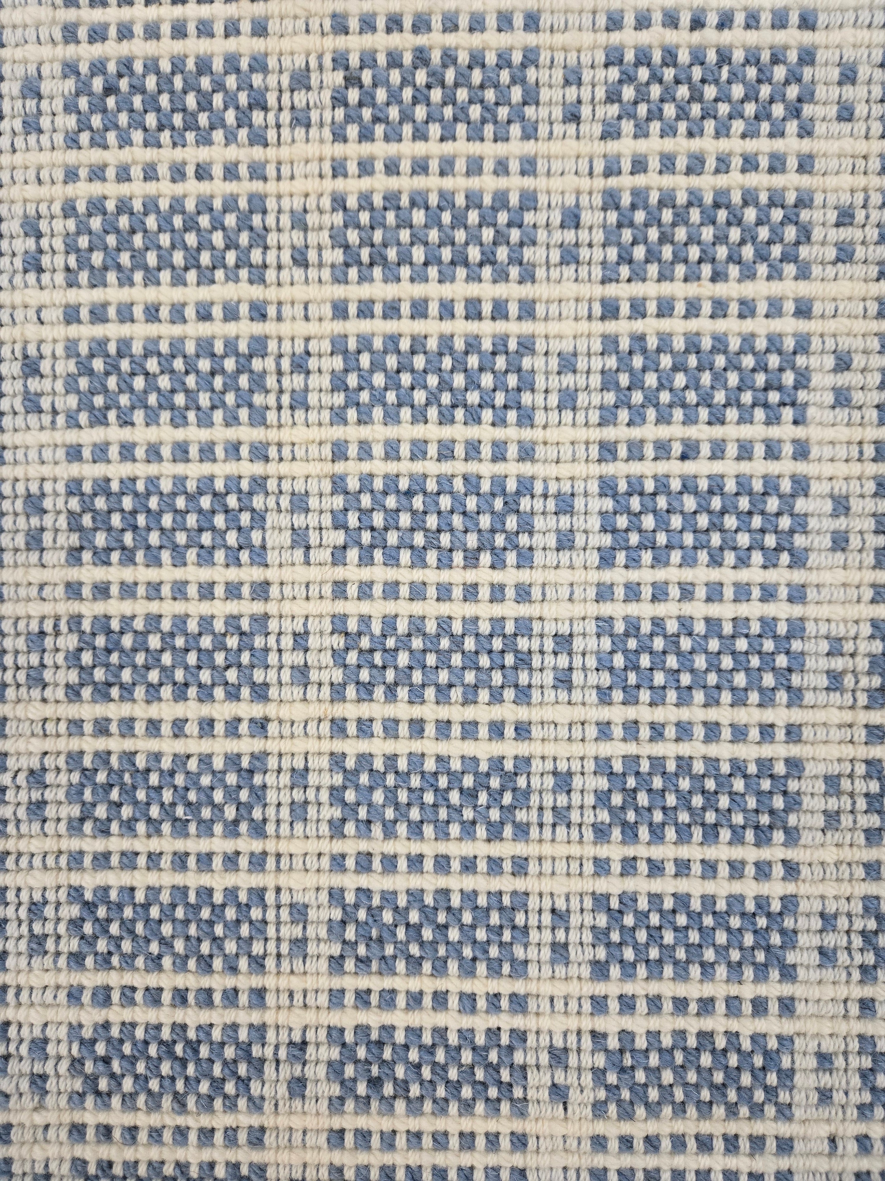 Broadloom carpet in slim plaid pattern in cream and blue.