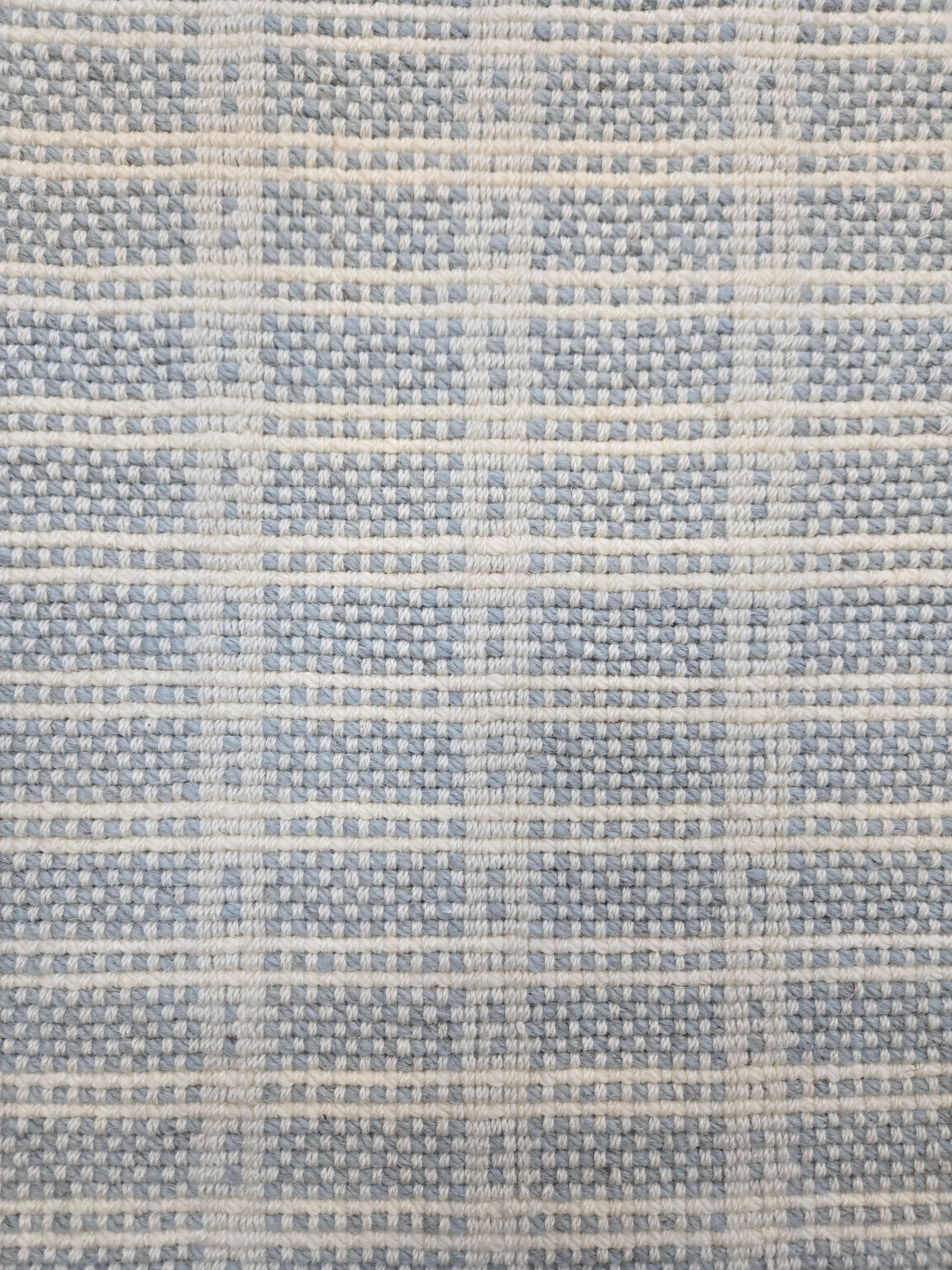 Broadloom carpet in slim plaid pattern in cream and light blue.