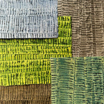 Pile of wallpaper swatches with undulating ribbon patterns in shades of blue, green, gray and brown.