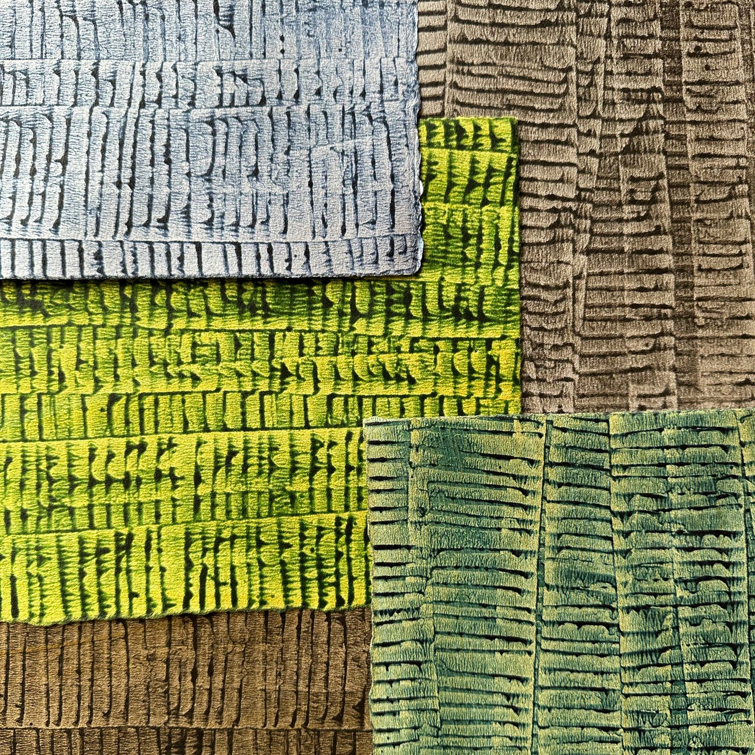 Pile of wallpaper swatches with undulating ribbon patterns in shades of blue, green, gray and brown.