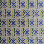 Close up printed fabric with green squiggles, white striped triangles, blue X marks on a broken grid in orange on a white background. 